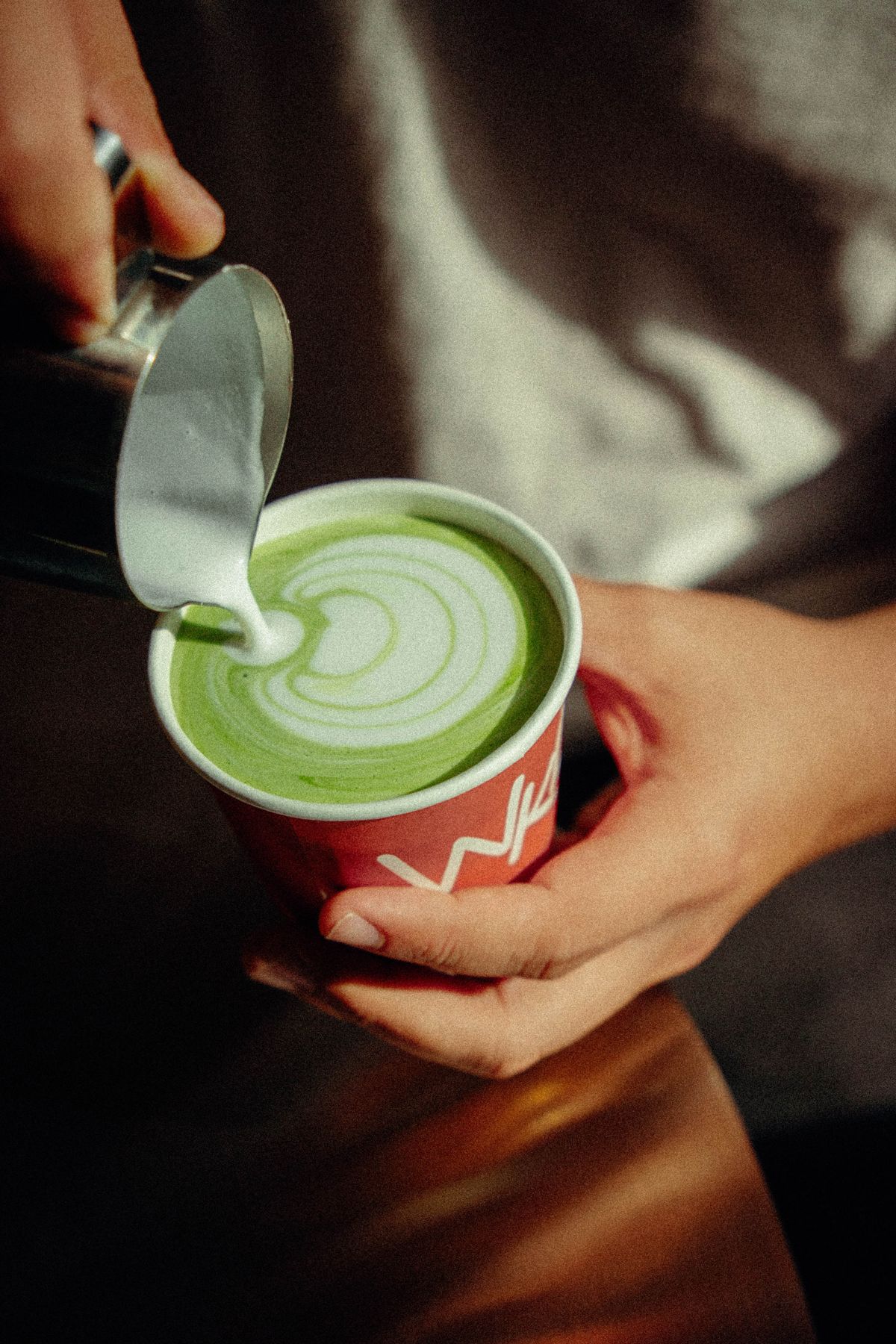 Steamed milk poured into a bright green matcha latte
