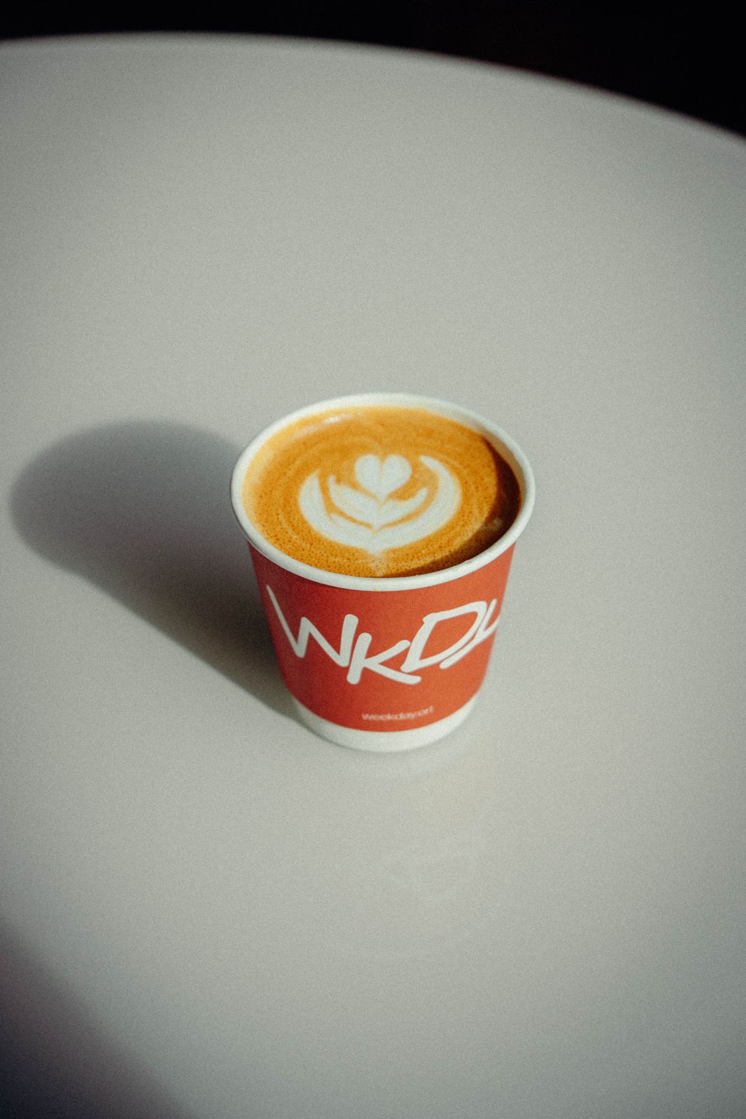 A hot latte with tulip latte art in a red Weekday cup