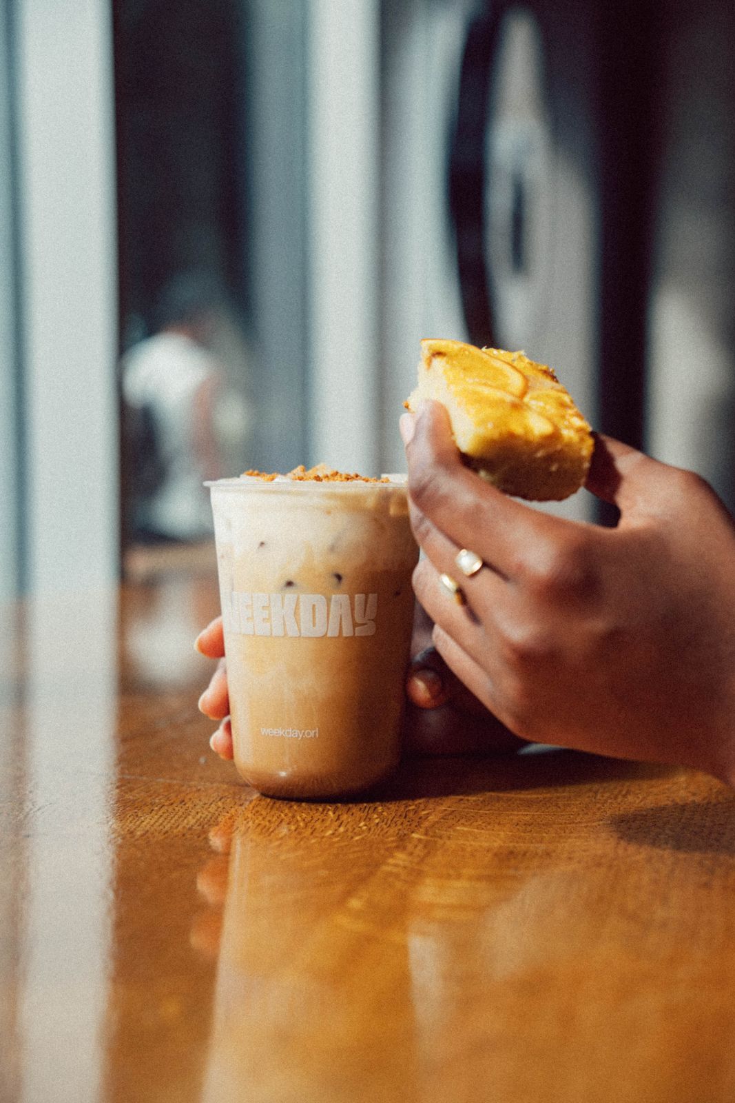 An iced latte in a Weekday cup beside a slice of seasonal Citronaut Cake
